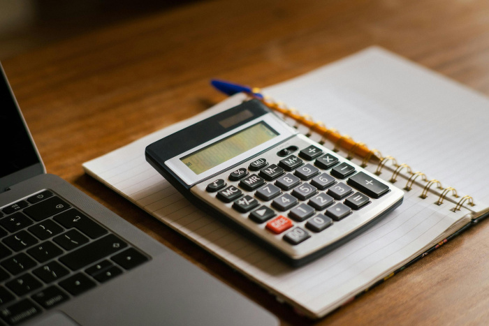 a laptop and a notebook pencil and calculator on a wooden table