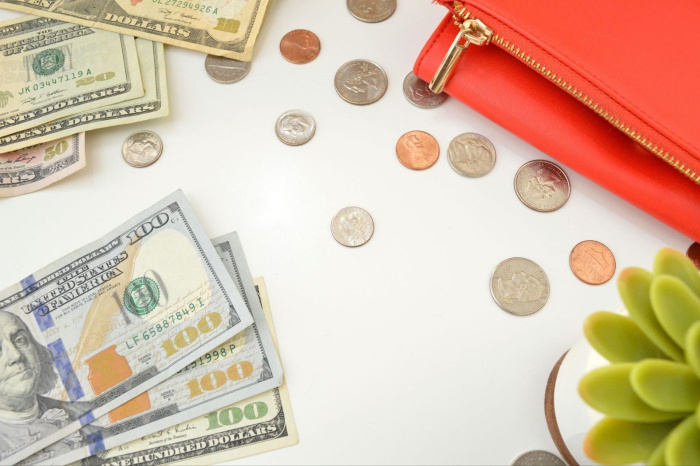 coins on a table with a wallet and plant