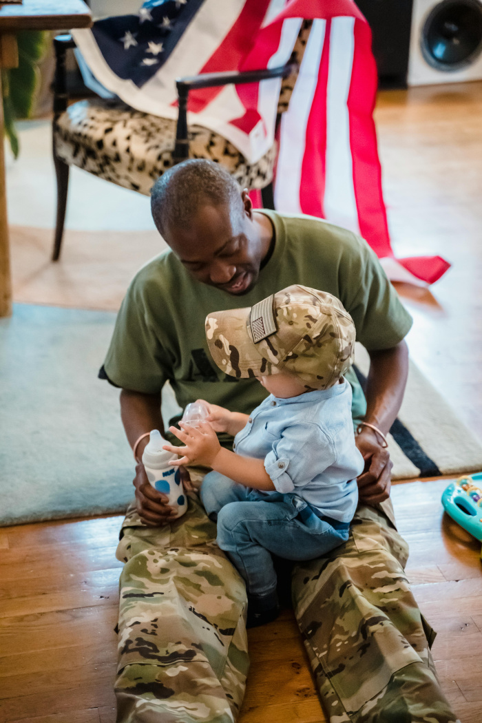 an active duty service memeber holding his baby in his new home