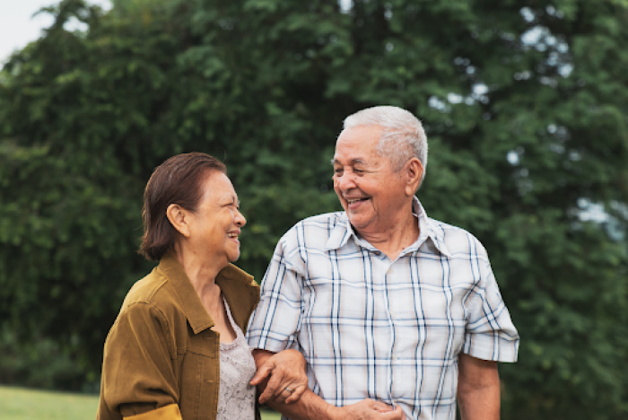 an older couple smiles at each otehr walkign outside