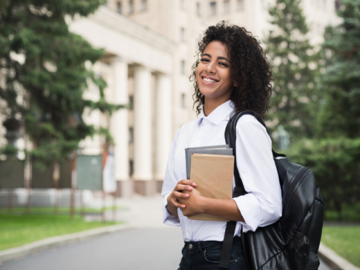 a woman in a white shirt holding books after securing her small business loan in houston with essential credit union