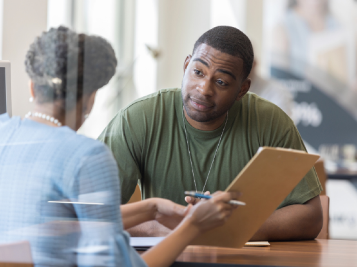 a woman helping a man in a green shirt secure his business loan in houston with essential credit union