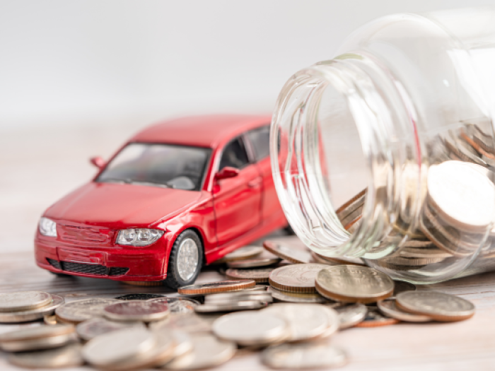 a red toy car near a pile of coins coming out of glass jar - auto loans in walker