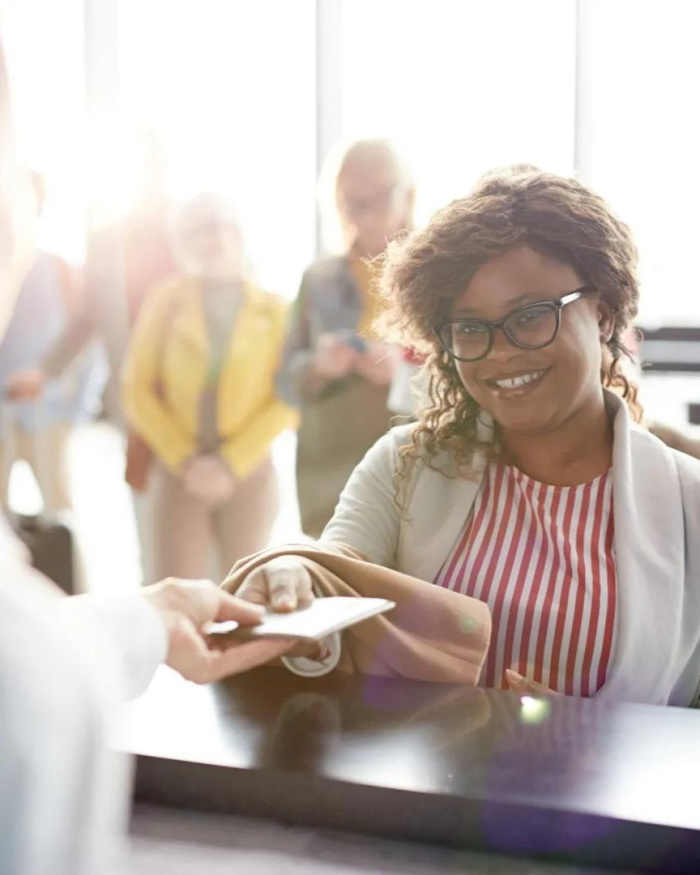 A woman passing a piece of white paper for a share certificate through a credit union teller window at Essential Credit Union Baton Rouge