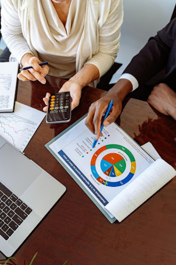 two people looking at spread sheets with data charts and calculator